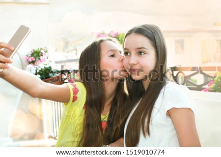 Outdoor funny portrait of two teen girls making grimaces flirting and showing tongue, posing on camera. Concept of stylish outfits friendship, joy, sisters, positive.