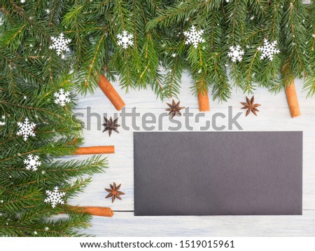 Fir tree branch with anise, cinnamon, black envelope on white wooden background. Winter holidays concept