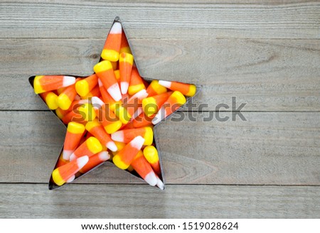 a star shaped metal cookie cutter filled with Halloween candy corn on a wood background with copy space
