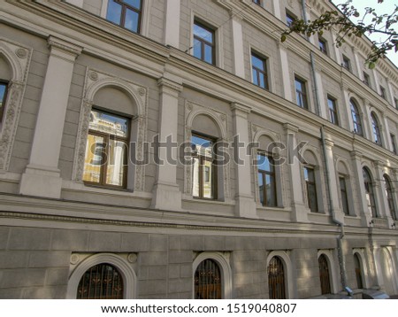 A yellow building reflected in the Windows of a gray stone house Royalty-Free Stock Photo #1519040807