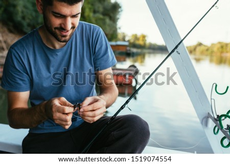 young man preparing fishing bait outdoors on river