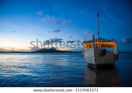 Scenic night view of traditional wooden Brazilian boat anchored in the waters off the shore of a remote island village in Bahia, Nordeste Brazil