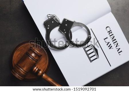 Judge's gavel, handcuffs and Criminal law book on grey background, flat lay