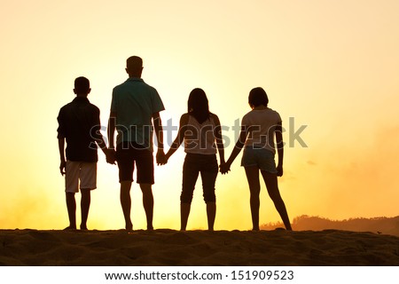 Family of four silhouette by a sunset