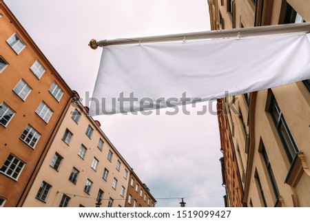 Horizontal white empty banner on clothes shop front against old buildings in city