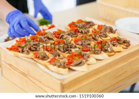 A cook in blue latex gloves is making sandwiches with meat and salmon Royalty-Free Stock Photo #1519100360