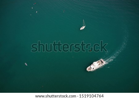Aerial view of a white boat sailing in the blue sea. Water transportation and summer leisure time activity.