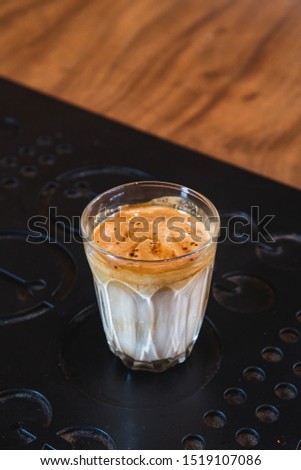 Coffee with milk in small  glass on black steel background