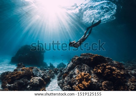 Woman freediver with fins underwater. Freediving and beautiful light in blue ocean Royalty-Free Stock Photo #1519125155