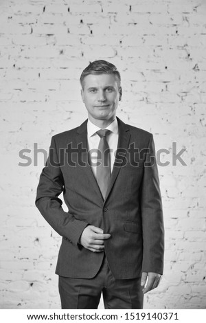 Black and white photo of businessman standing against brick wall