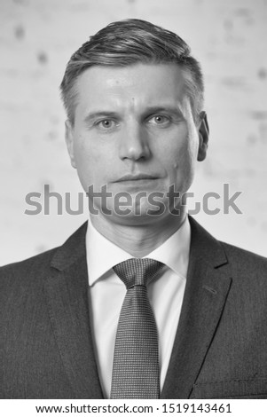 Black and white photo of mature businessman against brick wall