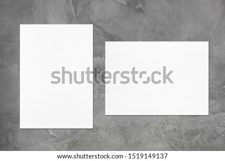 Two empty white vertical and horizontal rectangle poster or card mockups with soft shadows on dark grey concrete background. Flat lay, top view