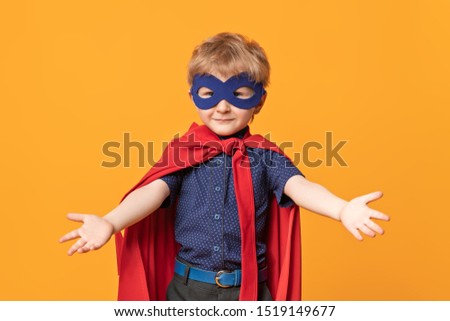 A portrait of a funny happy young boy posing in the costume of superhero. Kids development and education concept.