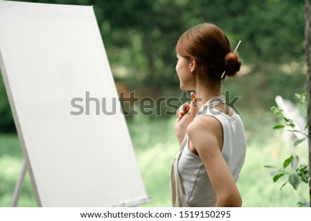 young woman with a white canvas on nature painting