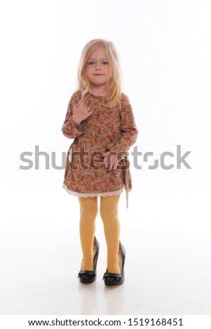 A little blonde girl in mom's shoes.