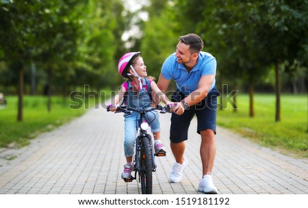 happy family father teaches child daughter to ride a bike in the Park in nature
