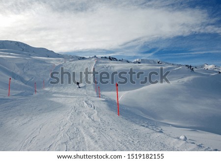 Blue ski piste in the ski resort of Bad Ragaz in Switzerland in winter against the backdrop of ski slopes, snow-capped mountains and a blue sky with clouds
