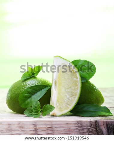Green limes with leaves on wooden background