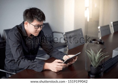 Young Asian businessman using digital tablet in office meeting room. Male entrepreneur reading news on social media app. Online marketing and Big data technology for E-commerce business. 