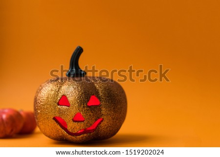 Scary shiny Halloween pumpkin toy. Jack-o'-lantern on an orange background with red luminous eyes with a place for text.