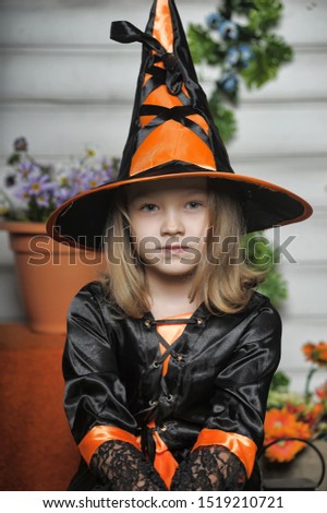 Portrait of girl in witch costume and small pumpkin.