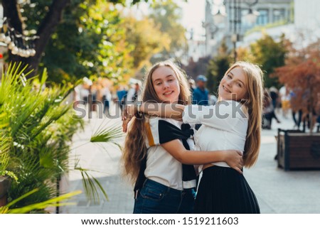 Happy brightful positive moments of two stylish girls hugging on street in city. Closeup portrait funny joyful attarctive young girls having fun, best friends.