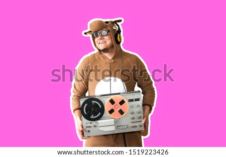 Man in cosplay costume of a cow with reel tape recorder isolated on purple background. Guy in the animal pyjamas sleepwear. Funny photo with party ideas. Disco retro music.