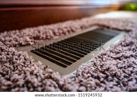 Focus on floor vent in room with carpet