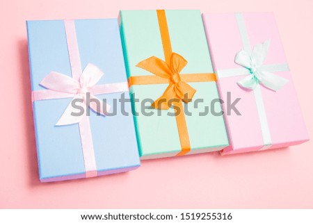 multi-colored boxes with bows on a pink background