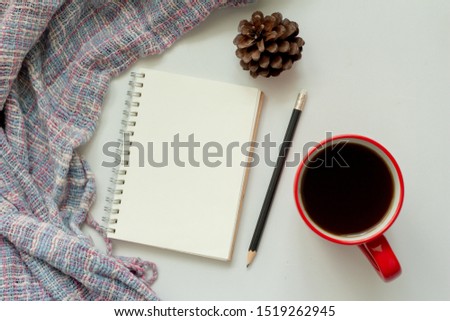 notebook with coffee,pine cone and scarf on wood table background,office desk. Autumn and winter. 