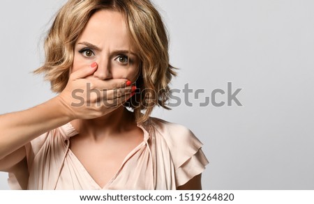 Isolated shot of speechless concerned shocked woman covers her mouth, looks shy, expressing silence and misconceptions, frightened