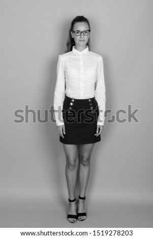Full length portrait of young beautiful businesswoman standing shot in black and white