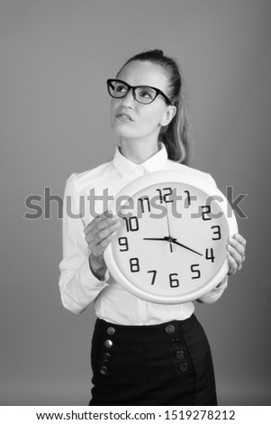 Portrait of young beautiful businesswoman holding clock
