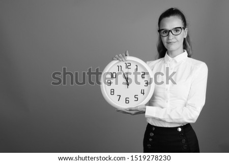 Portrait of young beautiful businesswoman holding clock