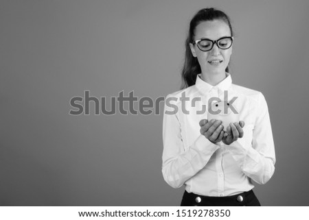 Portrait of young beautiful businesswoman holding piggy bank