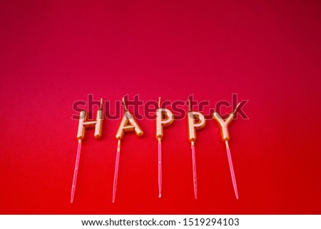 Happy candles on red paper background, isolated.