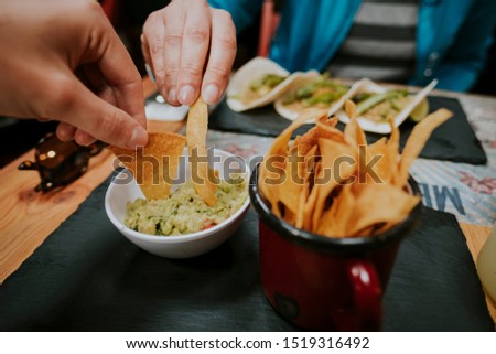 Two people eating nachos with guacamole in restaurant