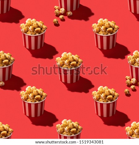 Popcorn in striped paper box on red background seamless pattern stock photo