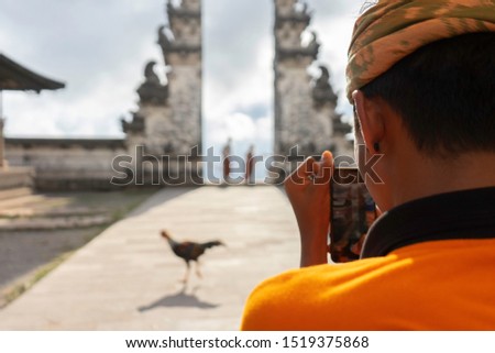 monk taking picture of tourists in pura lempuyang with rooster