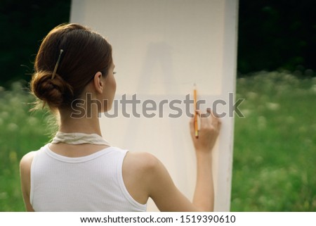 woman young easel in nature paints a picture