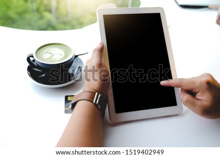 Close up of man using blank tablet and credit card sending massages on the coffee shop. 