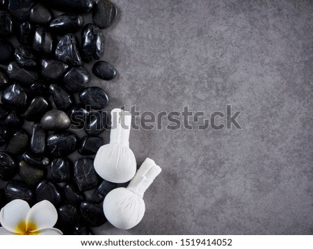 Beautiful spa composition with Herbal compress ball place on black pebbles on gray marble table. Top view, space for text.