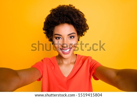 Photo of charming cute cheerful sweet nice girlfriend taking selfie recording video influencing her audiences while isolated over yellow bright color background