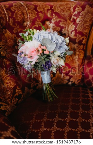 Bridal bouquet with pink roses and long ribbons on a red armchair.Beautiful wedding bouquet on an armchair