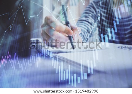 Financial forex graph drawn over hands taking notes background. Concept of research. Double exposure