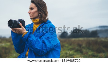 photographer tourist girl in blue raincoat hold in female hands photo camera take photography foggy mountain, traveler shooting autumn nature, click on camera technology, journey landscape