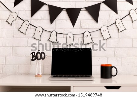 Workplace decorating for Halloween party with open laptop on table, blank screen for picture, copy space