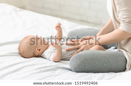 Baby healthcare. Woman massaging tummy of her son preventing colics, crop Royalty-Free Stock Photo #1519492406