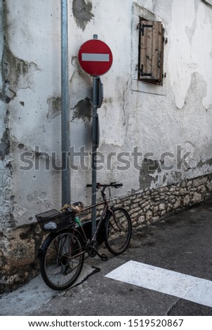 Old Bicycle Locked With Chain On Pole In Front Of Old House