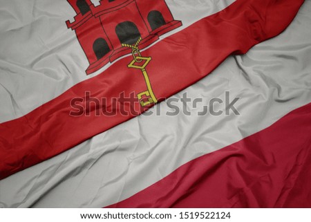 waving colorful flag of poland and national flag of gibraltar. macro